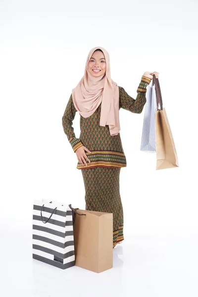 白い背景に隔離されたショッピングバッグを運ぶアジアの伝統的なドレス現代のクルンの美しいイスラム教徒の女子大生 Eidul Fitriファッションとお祝いのショッピングコンセプト — ストック写真