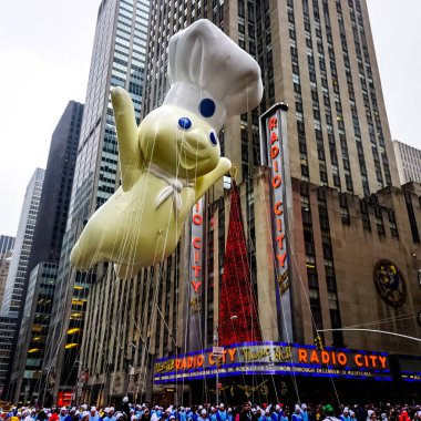 Pillsbury Doughboy balonu, Macy 'nin Şükran Günü geçit töreni sırasında havada süzülür. Arka planda Radio Music Hall ile birlikte Amerika Bulvarı boyunca. Manhattan, New York, ABD 27 Kasım 2014.