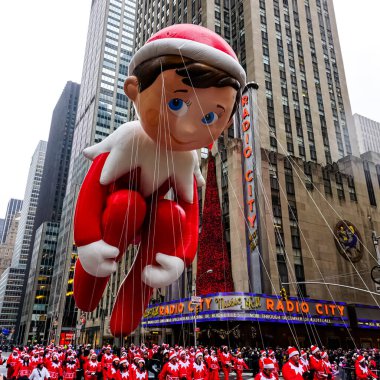Raftaki Elf balonu Macy 'nin Şükran Günü geçit töreninde havada süzülür. Arka planda Radio Music Hall ile birlikte Amerika Bulvarı boyunca. Manhattan, New York, ABD 27 Kasım 2014