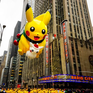 Pikachu pokemon balonu, Macy 'nin Şükran Günü geçit töreni sırasında havada süzülür. Arka planda Radio Music Hall ile birlikte Amerika Bulvarı boyunca. Manhattan, New York, ABD - 27 Kasım 2014.