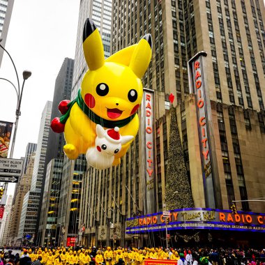 Pikachu pokemon balonu, Macy 'nin Şükran Günü geçit töreni sırasında havada süzülür. Arka planda Radio Music Hall ile birlikte Amerika Bulvarı boyunca. Manhattan, New York, ABD - 27 Kasım 2014.