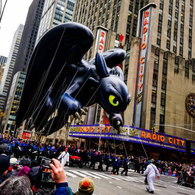 Dişsiz Ejderha balonu Macy 'nin Şükran Günü geçit töreni sırasında havada süzülür. Arka planda Radyo Müzik Salonu ile birlikte Amerika Bulvarı boyunca. Manhattan, New York, ABD 27 Kasım 2014