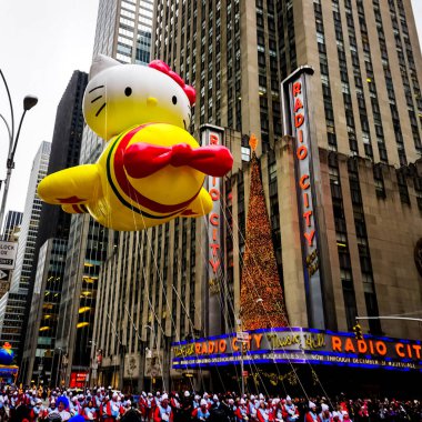 Hello Kitty balonu, Macy 'nin Şükran Günü geçit töreni sırasında havada süzülür. Arka planda Radio Music Hall ile birlikte Amerika Bulvarı boyunca. Manhattan, New York, ABD 27 Kasım 2014