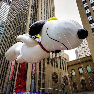 Snoopy balonu her yıl düzenlenen Macy 'nin Şükran Günü geçit töreninde havada süzülüyor. Arka planda Radyo Müzik Salonu var. Manhattan, New York, ABD - 27 Kasım 2014.
