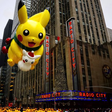 Pikachu pokemon balonu, Macy 'nin Şükran Günü geçit töreni sırasında havada süzülür. Arka planda Radio Music Hall ile birlikte Amerika Bulvarı boyunca. Manhattan, New York, ABD - 27 Kasım 2014.