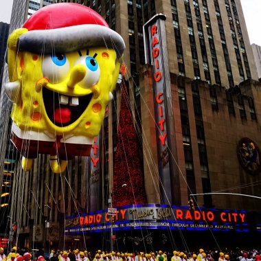 Sünger Bob Kare Karıncalı balon, Macy 'nin Şükran Günü geçit töreni sırasında havada süzülür. Arka planda Radio Music Hall ile birlikte Amerika Bulvarı boyunca. Manhattan, New York, ABD 27 Kasım 2014