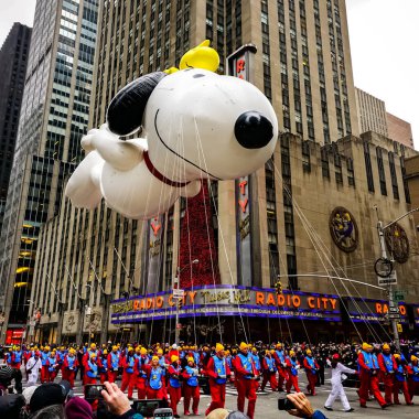 Snoopy balonu her yıl düzenlenen Macy 'nin Şükran Günü geçit töreninde havada süzülüyor. Arka planda Radyo Müzik Salonu var. Manhattan, New York, ABD - 27 Kasım 2014.