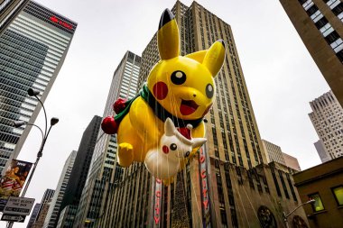 Pikachu pokemon balonu, Macy 'nin Şükran Günü geçit töreni sırasında havada süzülür. Arka planda Radio Music Hall ile birlikte Amerika Bulvarı boyunca. Manhattan, New York, ABD - 27 Kasım 2014.