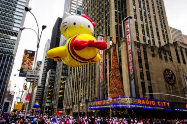 Hello Kitty balonu, Macy 'nin Şükran Günü geçit töreni sırasında havada süzülür. Arka planda Radio Music Hall ile birlikte Amerika Bulvarı boyunca. Manhattan, New York, ABD 27 Kasım 2014
