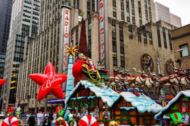 Noel Baba, Macy 'nin Şükran Günü geçit töreninde arka planda Radyo Müzik Salonu olan Amerika Bulvarı boyunca. Manhattan, New York, ABD - 27 Kasım 2014.