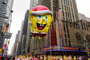Sünger Bob Kare Karıncalı balon, Macy 'nin Şükran Günü geçit töreni sırasında havada süzülür. Arka planda Radio Music Hall ile birlikte Amerika Bulvarı boyunca. Manhattan, New York, ABD 27 Kasım 2014