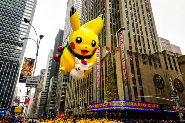 Pikachu pokemon balonu, Macy 'nin Şükran Günü geçit töreni sırasında havada süzülür. Arka planda Radio Music Hall ile birlikte Amerika Bulvarı boyunca. Manhattan, New York, ABD - 27 Kasım 2014.