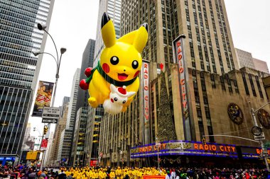 Pikachu pokemon balonu, Macy 'nin Şükran Günü geçit töreni sırasında havada süzülür. Arka planda Radio Music Hall ile birlikte Amerika Bulvarı boyunca. Manhattan, New York, ABD - 27 Kasım 2014.