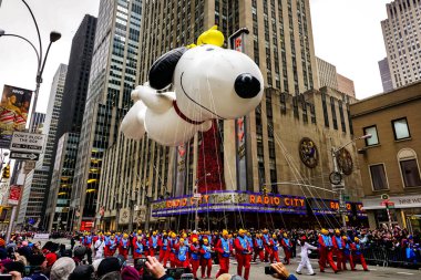 Snoopy balonu her yıl düzenlenen Macy 'nin Şükran Günü geçit töreninde havada süzülüyor. Arka planda Radyo Müzik Salonu var. Manhattan, New York, ABD - 27 Kasım 2014.