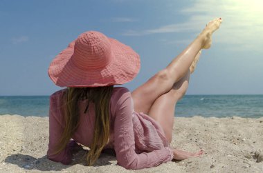 Büyük kırmızı şapkalı kum plajda yatan genç kadın. Deniz kenarında tatil yaz.