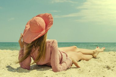 Büyük kırmızı şapkalı kum plajda yatan genç kadın. Deniz kenarında tatil yaz.