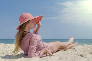 Büyük kırmızı şapkalı kum plajda yatan genç kadın. Deniz kenarında tatil yaz.