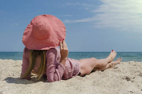 Büyük kırmızı şapkalı kum plajda yatan genç kadın. Deniz kenarında tatil yaz.