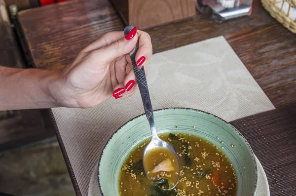 Young woman eating seafood soup. Female hand holding a spoon with fresh soup. Lunch concept. Copy space
