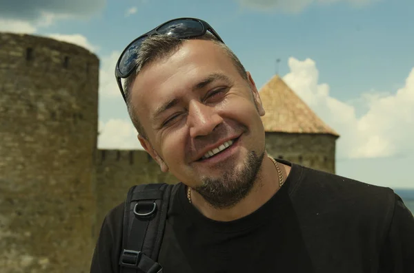 smiling man against the background of an ancient fortress in summer