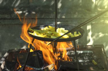 Kavrulmuş Fransız kızarmış patates Barbekü piknik için yemek. Büyük bir tavada duman ile açık bir yangın Barbekü patates kızartması. Gevrek fırın fırında patates kızartması tehlikede