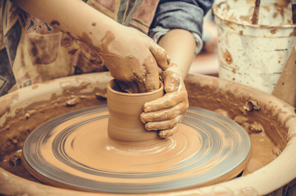 Hands of a potter. Potter making ceramic mug on the pottery wheel