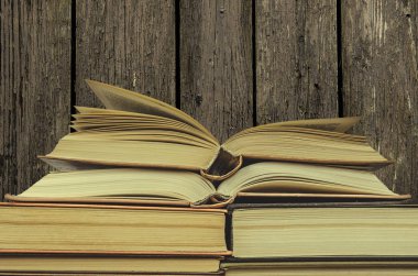 Ahşap arka plan üzerinde kitap yığını. pek çok kitap yığınları. İki açık kitap