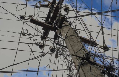 Bulutlar yakın çekim ile mavi gökyüzüne karşı beton elektrik direği. Bir ayağı ve mavi gökyüzü bir tel.