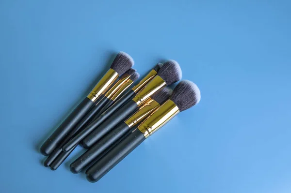 Pincéis de maquiagem em um fundo azul — Fotografia de Stock