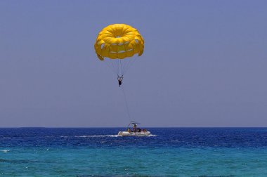 Sarı bir paraşütle uçan paraşütçü