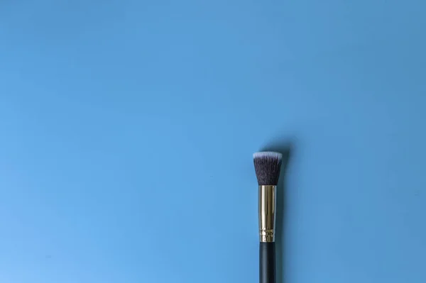 Pincel de maquiagem em um fundo azul — Fotografia de Stock