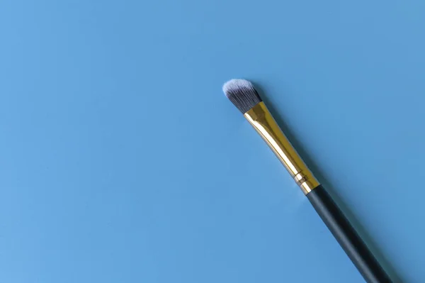 Pincel de maquiagem em um fundo azul — Fotografia de Stock