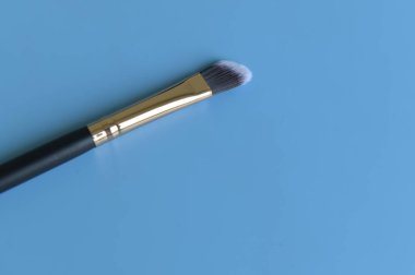 Mavi arka planda makyaj fırçası