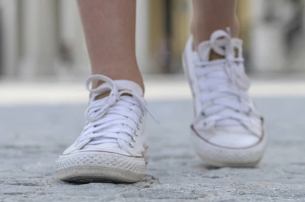 Крупный план женских ног в белых кроссовках — стоковое фото