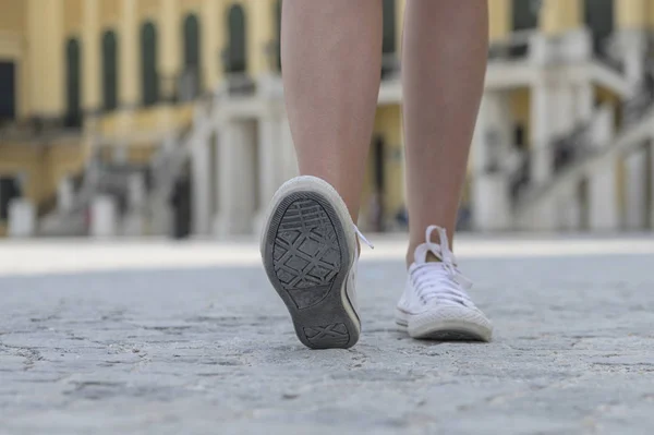 Primer plano de las piernas femeninas con zapatillas blancas —  Fotos de Stock