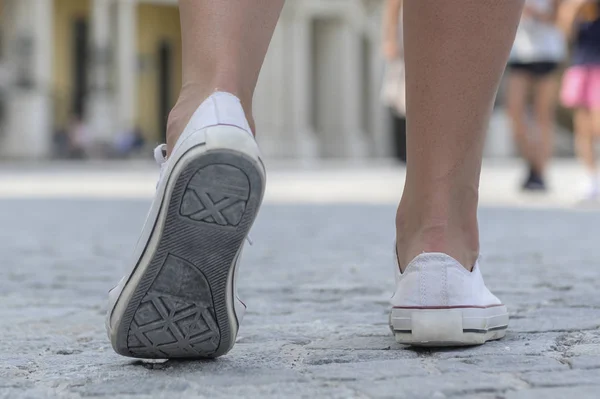 Primer plano de las piernas femeninas con zapatillas blancas —  Fotos de Stock