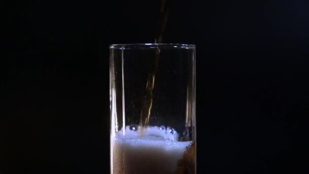 黒い背景のガラスのクローズアップにコーラを注ぐ 水滴のついたガラスの中の冷たいコーラ スローモーション — ストック動画