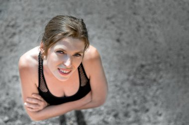 Genç bir kadının üst görünüm portresi. Kadın sokakta durur ve gülümser..