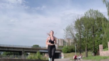 Genç bir kadın nehir kenarında koşup koştuktan sonra dinleniyor. Şehirdeki bir kardiyo egzersizinden sonra yorgun düşmüş güzel bir bayan sporcu. Koşu yaşam tarzı sağlıklı yaşam tarzı.