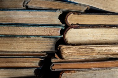 Bir yığın eski antika kitap. Antika kitapları sıcak yönlü ışıkta birikir.