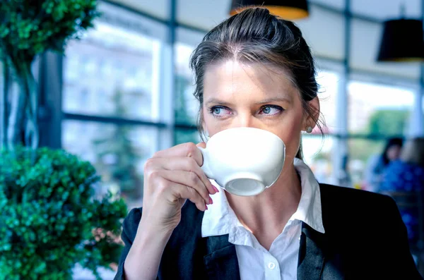 Business woman drinking coffee in a cafe. Portrait of young woman drinking tea.