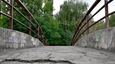 Eski terk edilmiş beton köprü. Parlak güneş ışığı altında arkaplanda ağaçlar olan çatlamış betonla köprü içi