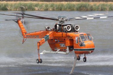 Bundoora, Australia - December 30, 2019: Erickson Air Crane helicopter filling with water to fight a bushfire in the Melbourne suburb of Bundoora. clipart
