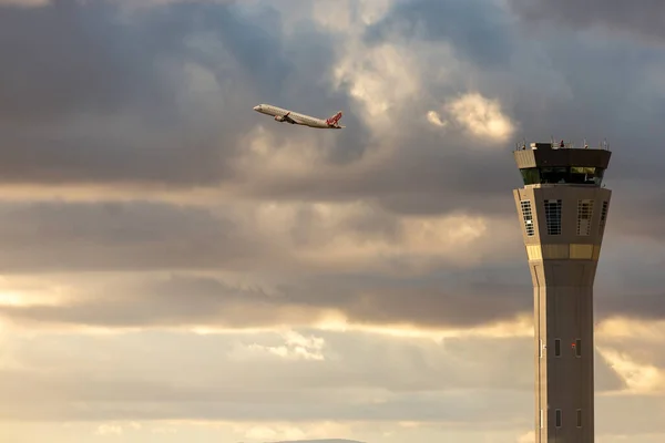 Melbourne, Avustralya - 19 Ocak 2020: Melbourne Havaalanı Hava Trafik Kontrol Kulesi, günbatımında Virgin Avustralya Havayolları Embraer bölgesel jeti arka planda kalkıyor.. 