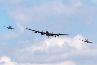 RAF Waddington, the UK - 5 Temmuz 2014: Royal Air Force (RAF) Battle of Britain Memorial Flight Avro Lancaster bombardıman uçağı PA474 iki Supermarine Spitfire avcı uçağı ile birlikte.