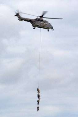 Payerne, Switzerland - August 30, 2014: Swiss Air Force Aerospatiale AS532 (TH98) military utility helicopter T-340 transporting troops by rope suspension.