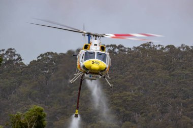Bundoora, Avustralya - 30 Aralık 2019: Bell 412 helikopteri bir yangınla savaşmak için su yükledikten sonra havalandı.