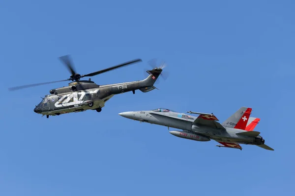 Payerne, İsviçre - 30 Ağustos 2014: İsviçre Hava Kuvvetleri Aerospatiale AS332 (TH89) askeri araç helikopteri T-316 İsviçre Hava Kuvvetleri McDonnell Douglas F / A-18C savaş uçağı formasyonda.