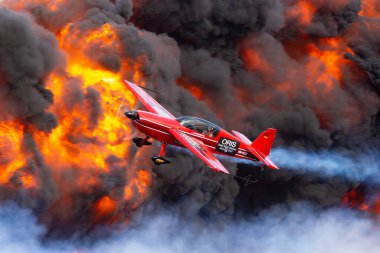 Avalon, Australia - February 28, 2015: Aerobatic pilot Melissa Pemberton (Melissa Andrzejewski) flying an Extra 300 aerobatic aircraft past a pyrotechnics explosion.  clipart