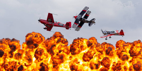 Avalon, Australia - February 26, 2015: Aerobatic pilots Melissa Pemberton, Skip Stewart and Jurgis Kairys flying in formation past a pyrotechnics explosions.